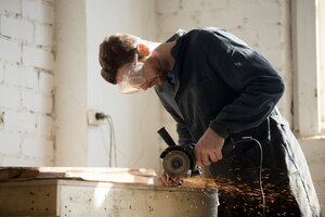Foto gratuita vista lateral del trabajador utilizando amoladora angular para el corte de metal