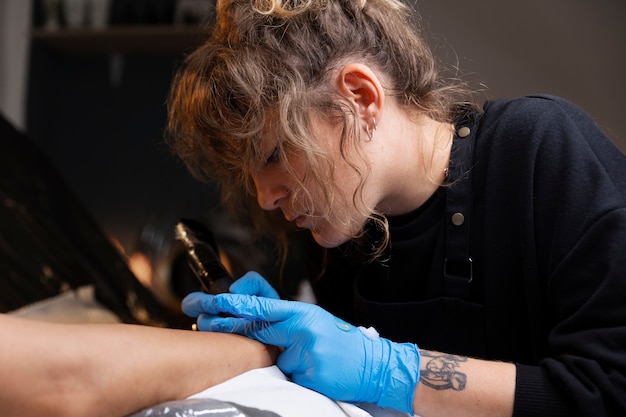 Foto gratuita vista lateral de trabajo del artista del tatuaje