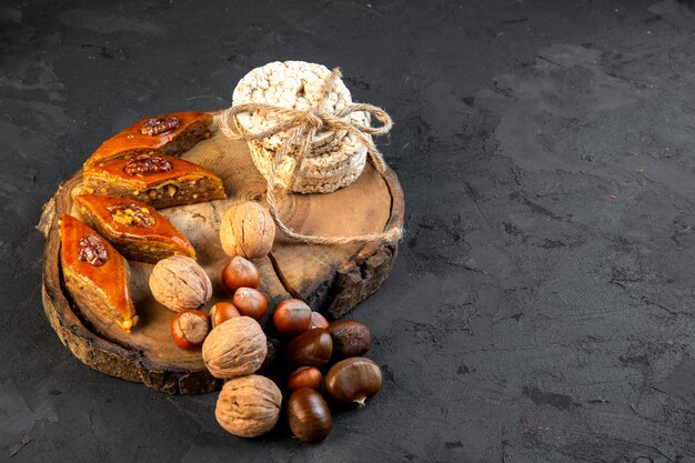 Vista lateral del tradicional baklava azerbaiyano con panes de arroz con nueces sobre tabla de madera sobre negro