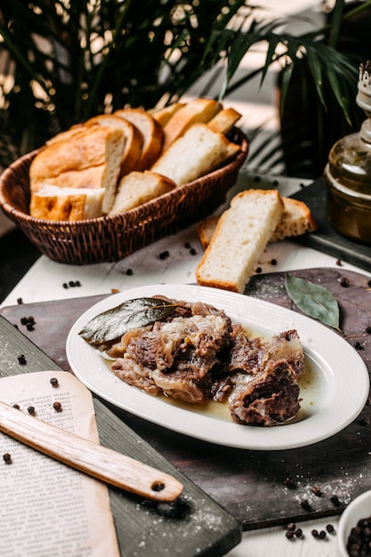 Vista lateral del tradicional buglama azerbaiyano en un plato blanco con hierbas