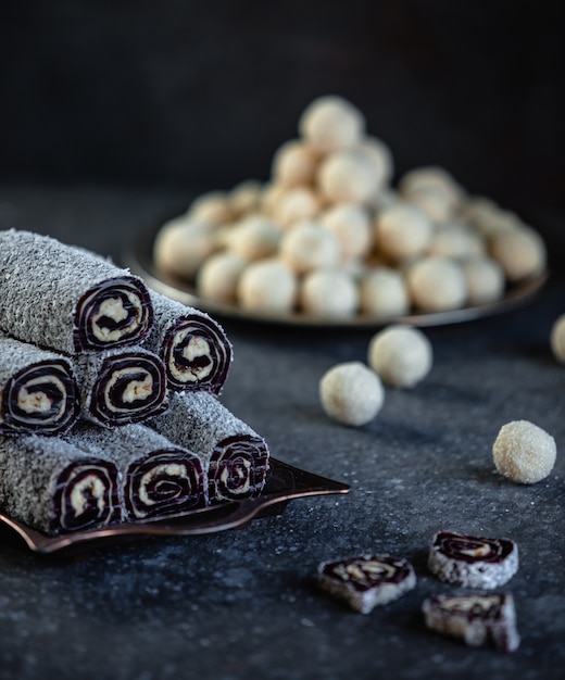 Foto gratuita vista lateral de la tradicional delicia turca lukum con hojuelas de coco en una bandeja en la pared negra