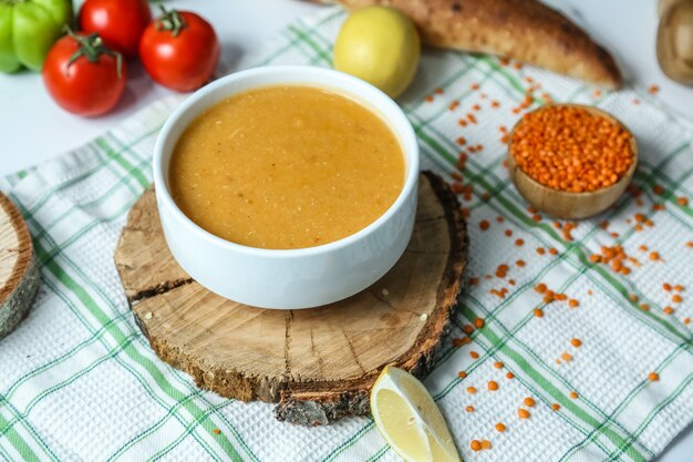 Vista lateral tradicional sopa de lentejas turcas con tomate y limón sobre la mesa