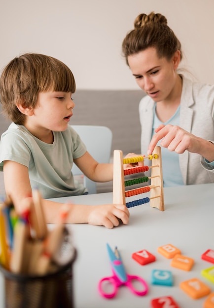 Vista lateral del tutor que le enseña al niño cómo usar un ábaco