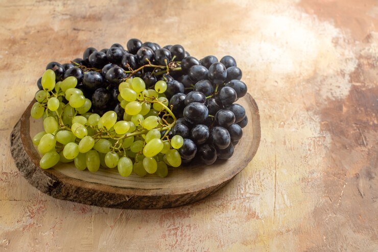 Foto gratuito vista lateral de las uvas las apetitosas uvas negras y verdes en la tabla de madera