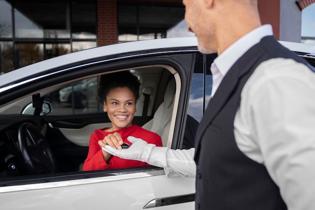 Foto gratuita vista lateral valet y mujer sosteniendo llave