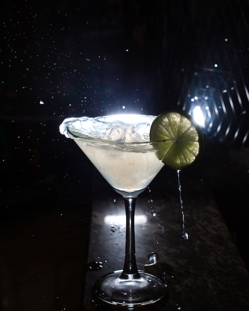 Vista lateral del vaso de martini con rodaja de limón en negro