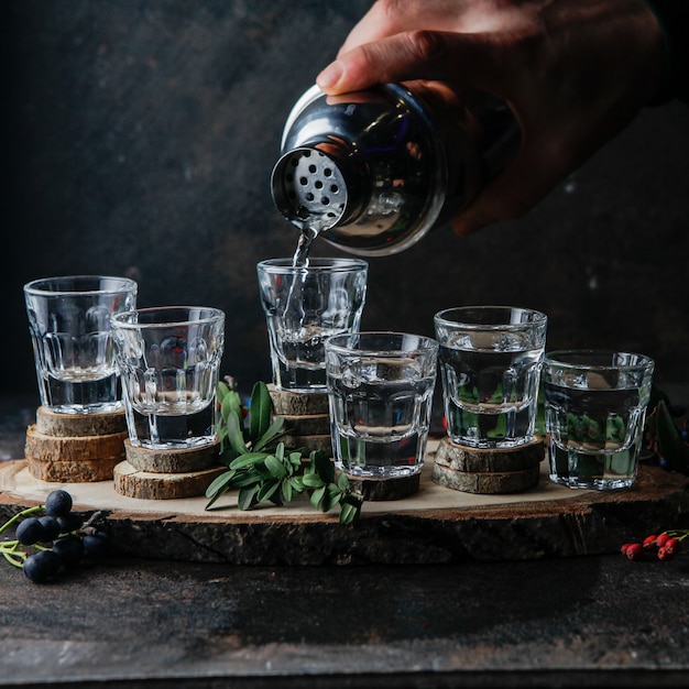 Foto gratuita vista lateral vasos de chupito con bebidas, barman vierte alcohol