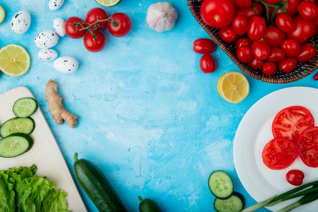 Vista lateral de verduras como huevo de tomate jengibre y otras con limón sobre superficie azul