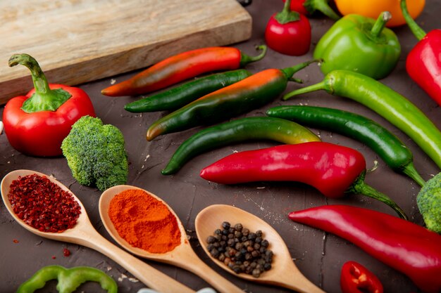 Vista lateral de verduras como pimienta, brócoli con especias en la superficie marrón