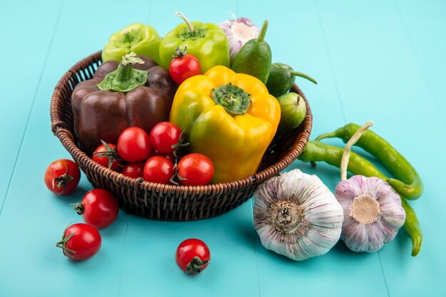 Vista lateral de verduras como pimiento tomate pepino ajo en canasta y azul