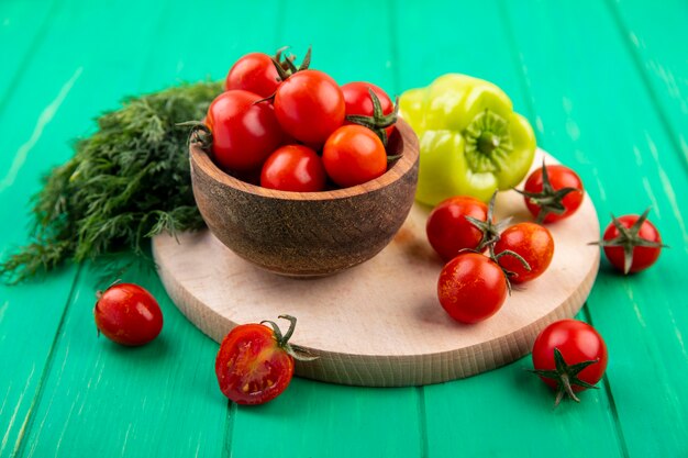 Vista lateral de verduras como plato de tomates y pimiento en la tabla de cortar con un montón de eneldo en verde