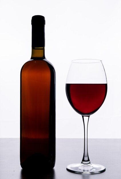 Vista lateral vino tinto con vidrio en blanco vertical