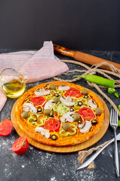 Vista lejana sabrosa pizza sabrosa con tomates rojos, aceitunas verdes y champiñones con tomates frescos por todo el escritorio gris
