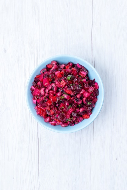 Vista lejana superior deliciosa ensalada de remolacha en rodajas con verduras dentro de la placa azul en el escritorio de luz, ensalada de salud de comida vegetal con vitamina