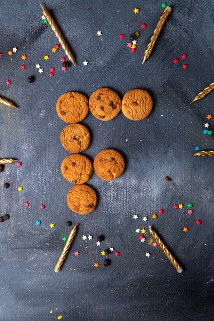 Vista lejana superior deliciosas galletas de chocolate con velas y decoraciones en el fondo gris oscuro galleta galleta té dulce azúcar