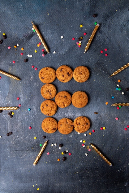 Vista lejana superior deliciosas galletas de chocolate con velas y decoraciones en el fondo oscuro galleta galleta té dulce azúcar