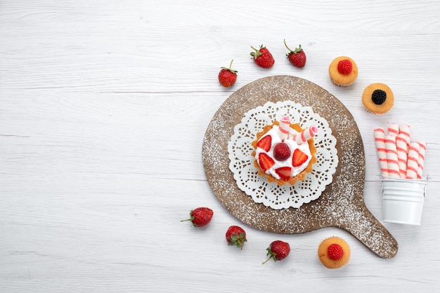 Vista lejana superior de la pequeña y deliciosa tarta con crema y tartas de fresas frescas rojas en rodajas en blanco, tarta de baya dulce hornear frutas