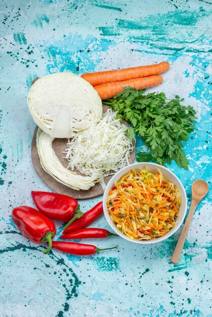 Vista lejana superior de verduras frescas en rodajas Ensalada de piezas largas y delgadas dentro del plato con verduras, repollo, pimientos en azul brillante, ensalada de verduras de comida.