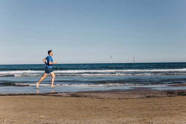 Vista de lejos de hombre corriendo en la playa