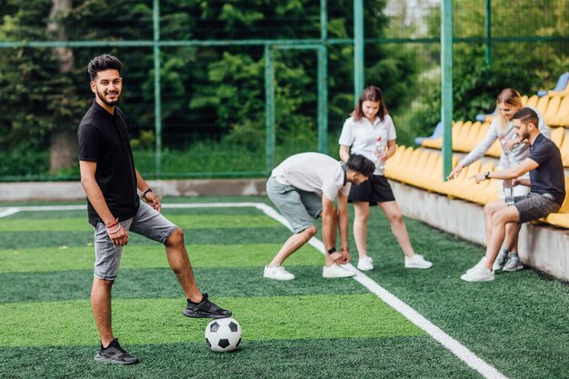 Vista de longitud completa del jugador de fútbol atlético afroamericano que se queda con la pelota en el campo verde