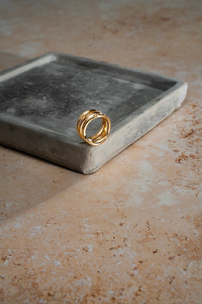 Foto gratuita vista del lujoso anillo dorado en una bandeja de roca o hormigón