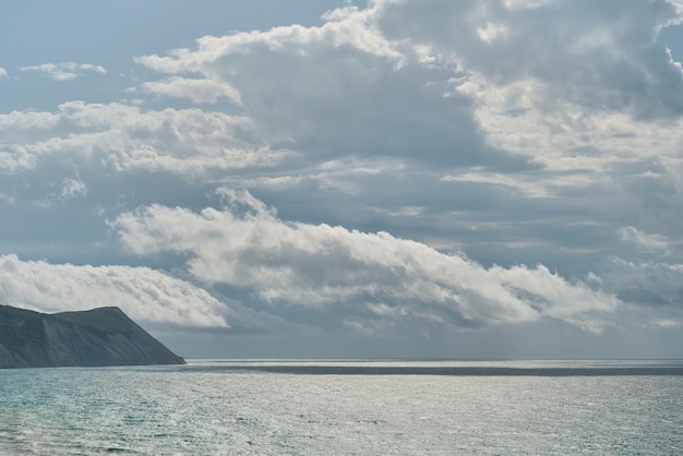 Vista del mar tormentoso y las rocas al fondo del mediodía o protector de pantalla para la pantalla Nubes sobre el mar en una tormenta