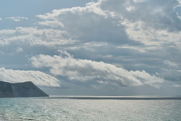 Vista del mar tormentoso y las rocas al fondo del mediodía o protector de pantalla para la pantalla Nubes sobre el mar en una tormenta
