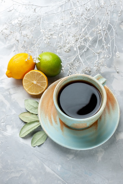 Vista media taza de té con limones frescos en el escritorio blanco fruta cítrica fresca exótica