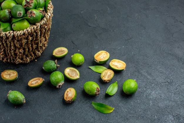 Vista de la mitad frontal feijoas frescas en canasta sobre superficie oscura