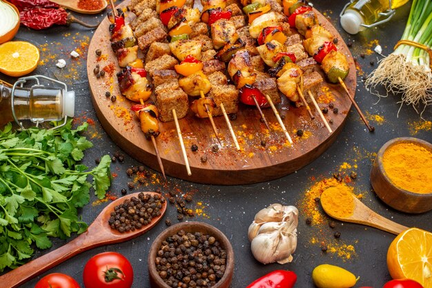 Vista de la mitad inferior deliciosas brochetas de pollo sobre tabla de madera y otras cosas en la mesa