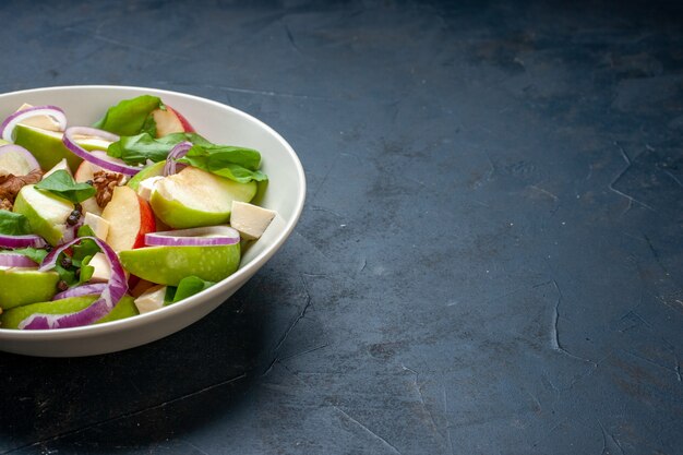 Vista de la mitad inferior ensalada de manzana fresca en un tazón en el lugar de copia de mesa azul oscuro