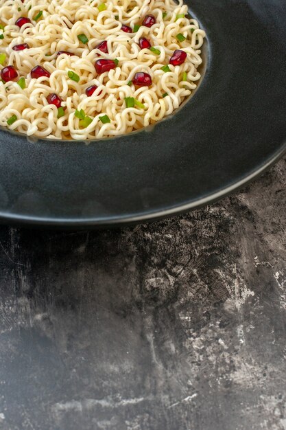 Vista de la mitad inferior de fideos ramen asiáticos en un plato redondo sobre una mesa oscura