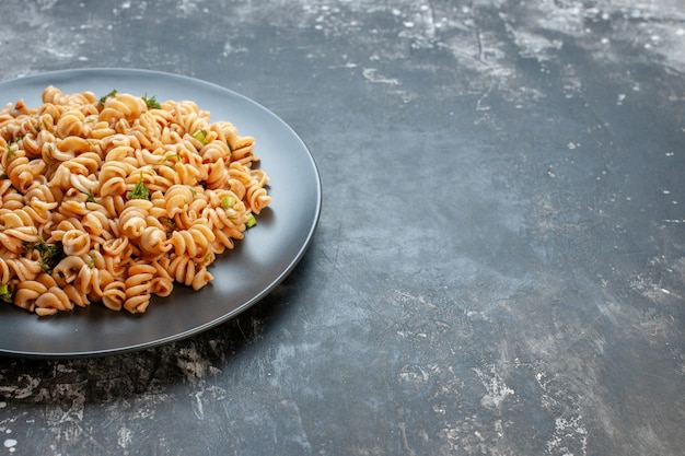 Foto gratuita vista de la mitad inferior de la pasta rotini en un plato redondo en el lugar de copia de superficie oscura