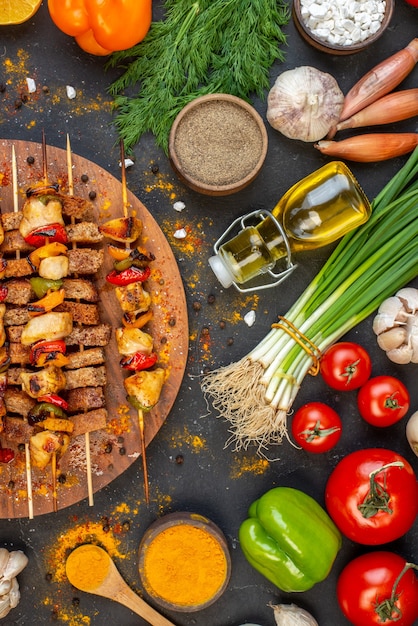 Vista de la mitad superior deliciosas brochetas de pollo sobre tabla de madera y otras cosas en la mesa