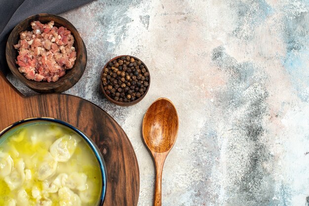 Vista de la mitad superior dushbara sobre tabla de cortar tazones de mantel negro con carne pimienta negra cuchara de madera sobre fondo desnudo espacio de copia