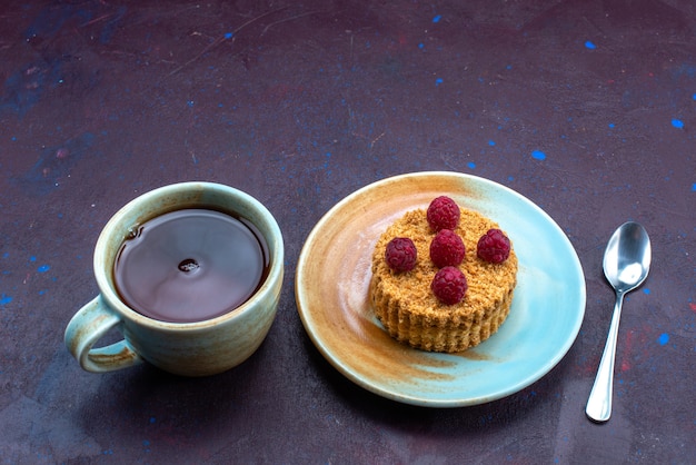 Foto gratuita vista de la mitad superior del pequeño pastel redondo con frambuesas frescas dentro de la placa con té en la superficie azul oscuro