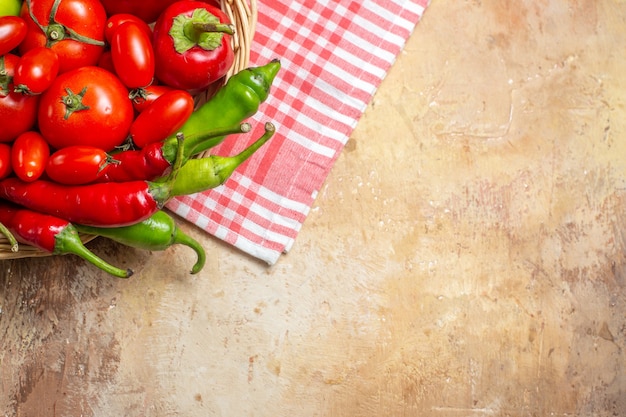 Vista de la mitad superior de pimientos verdes y rojos pimientos picantes tomates en canasta de mimbre y toalla de cocina sobre fondo ámbar