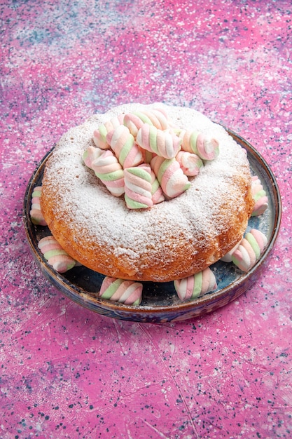 Vista de la mitad superior de la torta de azúcar en polvo con malvaviscos en la pared rosa