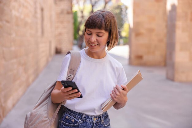 Vista de mujer estudiante con teléfono en la ciudad