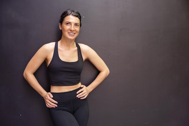 Foto gratuita vista de mujer morena quedándose cerca de la pared y sonriendo