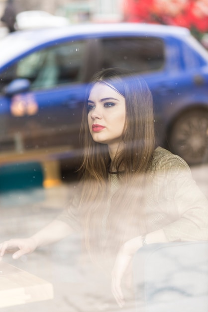 Vista de mujer a través de una ventana con reflejos de un coche