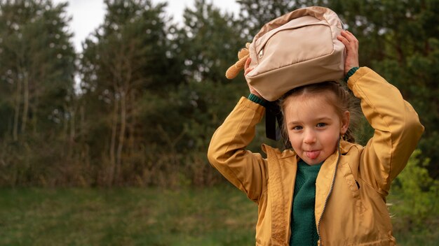 Vista de niña con mochila aventurándose en la naturaleza