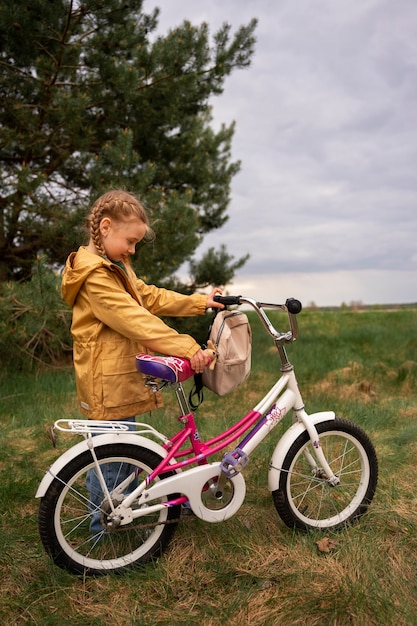 Vista de niña con mochila y bicicleta aventurándose en la naturaleza