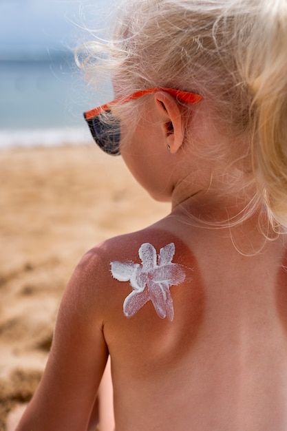 Foto gratuita vista de niña en la playa con loción en la piel quemada por el sol