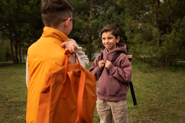 Foto gratuita vista de niños pequeños con mochilas pasando tiempo en la naturaleza al aire libre