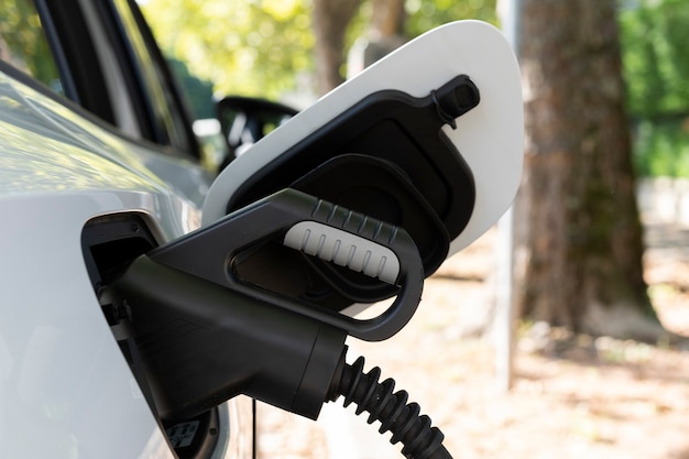 Vista del nuevo coche eléctrico blanco cargando en una estación