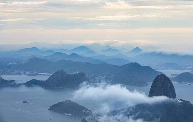 Vista de pájaro de un océano con montañas rodeadas de nubes