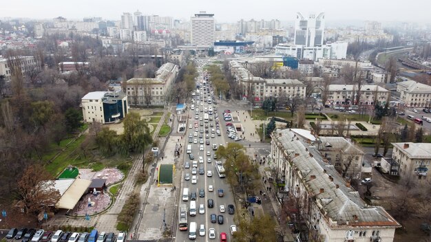 Vista panorámica aérea drone de Chisinau, calle con varios edificios residenciales y comerciales, camino con varios coches en movimiento, parque con árboles desnudos