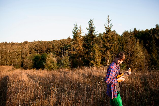 Vista panorámica del bosque y el hombre tocando el ukelele