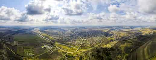 Foto gratuita vista panorámica de drones aéreos de un pueblo ubicado cerca de un río y colinas, campos, godrays, nubes en moldavia